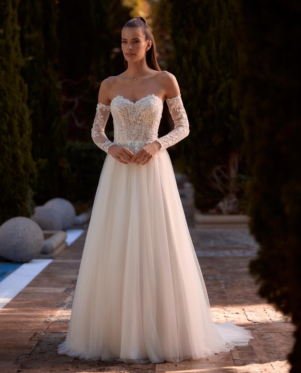 Vestido de Noiva Sofisticado & Versátil. Corpo estruturado em renda, decote coração e saia leve em tule, criando uma composição elegante e delicada. As mangas longas removíveis permitem transformar o visual e adaptar o vestido a diferentes momentos da celebração.